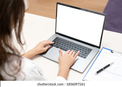 Mockup on laptop. Female doctor using laptop computer. Medical worker typing, browsing internet and sitting at work desk. Healthcare medical e health website technology concept. Close-up view.