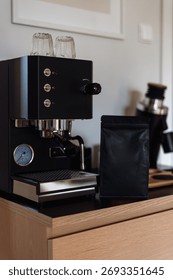 Mockup package with roasted beans. Vertical shot of a sleek black coffee machine is set up in a contemporary kitchen counter, brewing a fresh espresso while showcasing its professional features.