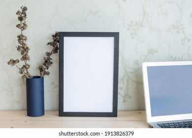 Mockup Of A Photo Frame With Dried Flowers In A Vase And Lap Top On A Wooden Table. Landscape Orientation.