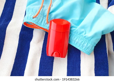 Mockup Of Red Glossy Deodorant Stick, Blank Roll For Deodorant, Striped Towel And Swim Shorts. 