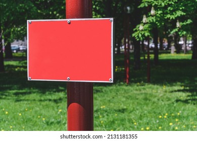 Mockup Of A Red Sign On A Pole. Against The Background Of The Park