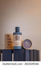 A Mock-up Of A Single Brown Bottle Of Men's Cologne With Its Brand Packaging. Product Is Photographed On A Brown Background In A Vertical Portrait Oriented View.