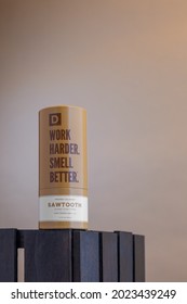 A Mock-up Of A Single Brown Bottle Of Men's Cologne Inside Its Brand Packaging. Product Is Photographed On A Brown Background In A Vertical Portrait Orientation View.