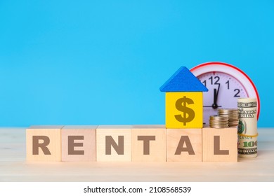 Mockup for a six-letter word on wooden cubes. A wooden house made of toy blocks, an alarm clock, coins and dollar bills. Yellow and blue toy house