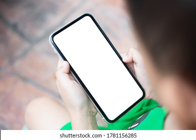 Mockup Smartphone With A Little Boy Holding And Watching Phone In Vertical Position With Isolated White Blank Screen, Top View. Kid Play Game, Surfing Online, Learning Background Concept.