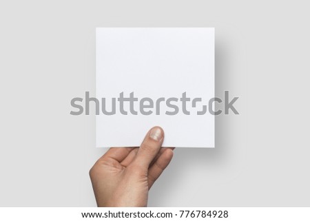 Mockup square empty blank white postcard holds the man in his hand. Isolated on a gray background