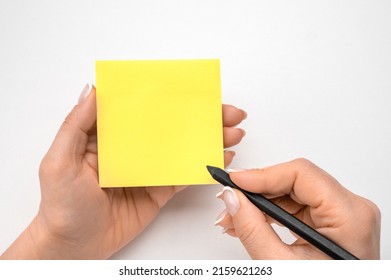 Mockup sticky Note Paper. Hand written notes black pencil on yellow sticker. white table background. woman hand writing on yellow sticky notes. female hand holding note paper and making note