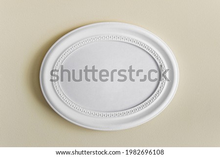 Mockup template with oval white textured photo frame with copy blank space hanging on yellow wall.