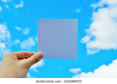 A mockup of the title frame held by a woman against the backdrop of a clear blue sky with floating clouds