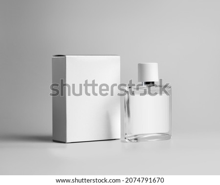Mockup of a transparent glass bottle for perfume, with a label for design, a white cardboard box for a branded scent, fragrance. Cosmetics advertising containers template isolated on background