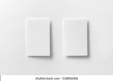 Mockup of two vertical business cards at white textured paper background.