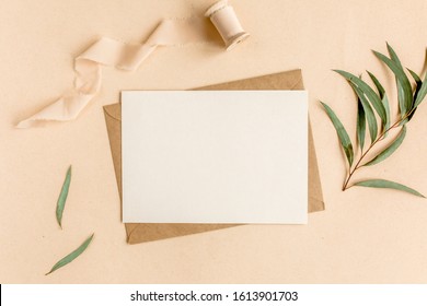 Mockup Wedding Invitation, Blank Greeting Card And Craft Envelope, Green Leaves Eucalyptus. Flat Lay, Top View.