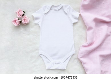 Mockup Of White Baby Bodysuit Shirt With Pink Rose And Pink Blanket On White Cotton Background. Design Bodysuit Template