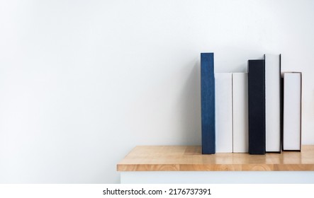 Mockup Of White And Blue Blank Book Spines On Wooden Shelf On White Background With Copy Space. Row Of Books With Empty Space Book Names Cover, Minimal Style.