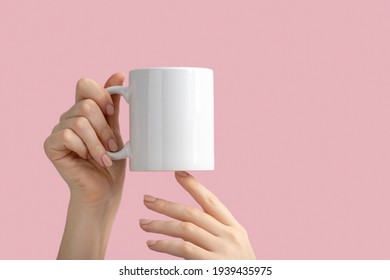 mockup white coffe cup or mug in female hands on pink background with copy space. Blank template for your design, branding, business. Real photo.