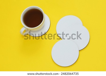 Mockup of white empty coasters and coffee cup on a yellow background