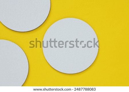 Mockup of white empty coasters for glasses or cups on a yellow background