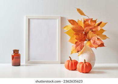 Mockup with a white frame and colorful autumn leaves in a vase on a light background. Empty poster frame mockup for presentation design, text, lettering - Powered by Shutterstock