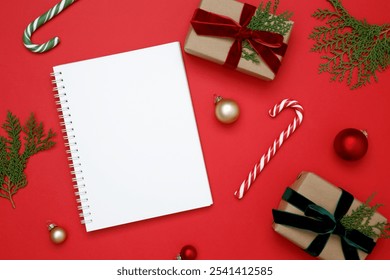 Mockup of white notebook surrounded by wrapped Christmas gifts and thuja branches in a festive setup - Powered by Shutterstock