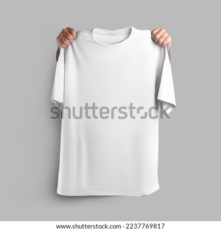 Mockup of white oversize t-shirt, clothes held in hands by shoulders, front view, for design, pattern, for advertising in online store. Template of sportswear, apparel close-up, isolated on background