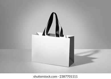 Mockup of a white paper bag without logo with black handles. White package on grey background