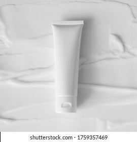 Mockup White Plastic Tube For Moisturizer, Lotion, Facial Cleanser Or Shampoo On Smudged Cream Texture Background Top View. Delicate Purity Skin Care Product