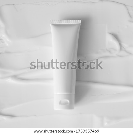 Mockup white plastic tube for moisturizer, lotion, facial cleanser or shampoo on smudged cream texture background top view. Delicate purity skin care product