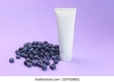 Mockup White Squeeze Bottle Cosmetic Tube And Blueberry A Lot Or Blueberries Heap On Violet Background. Moisturizer сream, Gel, Lotion, Balsam, Skin Care, Sunscreen. Front View, Blank Tube, Template