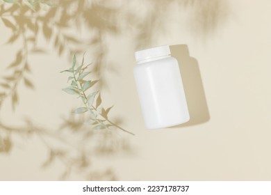 Mockup white vitamin bottle with leaves shadows top view, plant pills. Natural bio supplement, herbal vitamins.