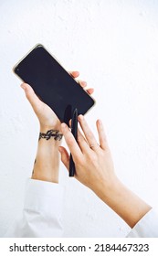 Mockup woman hand with tattoo using phone black blank screen on light background.