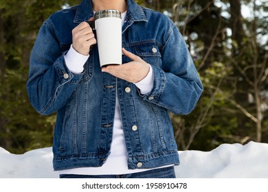 Mockup Of A Woman Wearing Denim Jacket Holding A White Travel Mug By A Snowy Woods. Empty Travel Coffee Mug With Handle Template, Model Mockup   