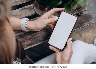 Mockup woman's hand holding using smart phone with white blank screen at coffee shop, mobile app design and advertising, online marketing