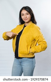 Mockup Women's Yellow Bomber Jacket-Portrait Of Young Hispanic Woman Pointing At Her Jacket On White Background