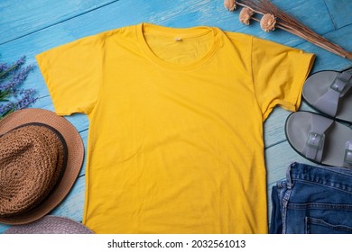 Mockup Of A Yellow T-shirt Blank Shirt Template With Accessories On The Blue Wooden Table Background, Lifestyle And Travel Concept