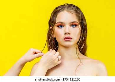 A Model With Bare Shoulders Bright Makeup On A Yellow Background Looks Into The Frame The Barber's Hands Are Doing Styling Hair Long In Oil Wet In Hair Gel Close Up