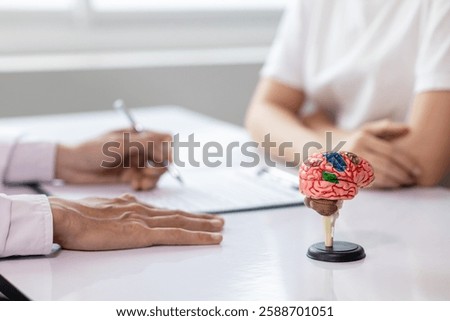 model brain which allows brain to be visualized and parts that are important and responsible for thought and memory is placed on doctor table to help explain problem areas of brain to the patient.