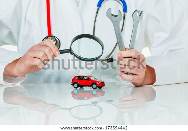 a model of a car is\
examined by a doctor. symbolic photo for workshop, service and car\
buying.