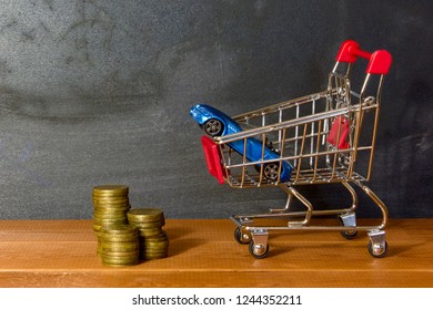 Model Car In  Grocery Cart On Background Of Drawing Boards And Coins. Concept Of Leasing, Auto Loan, Auto Insurance, Taxes, Car Purchase