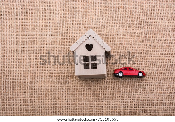 Model car and a little model house  on a\
canvas background