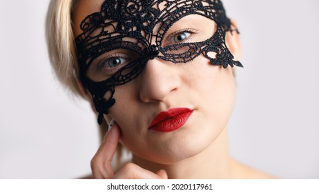 A model dressed in a masquerade ball costume for the fancy costume party looking at the camera. Wearing A Venetian Masquerade Mask and red lipstick. Mysterious girl wearing a lace Masquerade mask. - Powered by Shutterstock