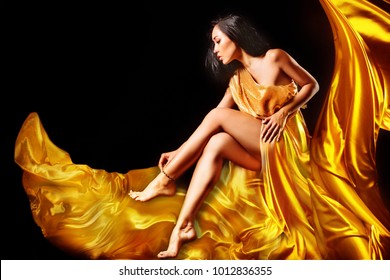 Model In A Gold Evening Dress Posing On A Black Background