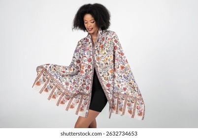 The model gracefully showcases a richly patterned shawl with vibrant floral motifs and intricate borders. Her poised expression and soft smile complement the shawl’s flowing elegance