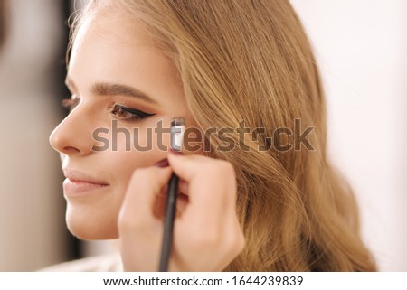 Model have a makeup by makeup artist in beauty salon. Close up of model's face with make up