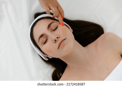 Model With A Headband And  With Lifting Tape On Her Face. Kinesio Taping.
She Covers Her Face With Duct Tape. A Young Woman With Ribbons On Her Face. An Aesthetic Patch For The Face. A Patch To Maint