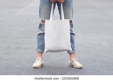model hold blank white fabric tote bag for save environment on street fashion