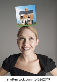 Model home on top of young woman's head representing homeownership