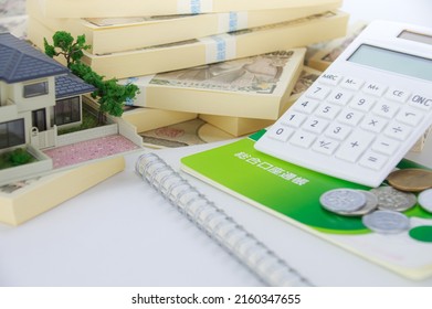 A Model Of A House, A Bunch Of Japanese Yen Bills, And A Japanese Savings Passbook