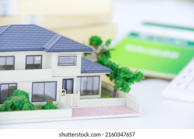 A Model Of A House, A Bunch Of Japanese Yen Bills, And A Japanese Savings Passbook