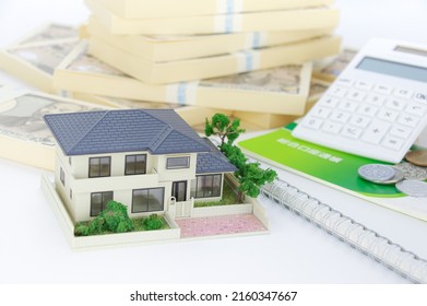 A Model Of A House, A Bunch Of Japanese Yen Bills, And A Japanese Savings Passbook