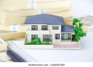 A Model Of A House, A Bunch Of Japanese Yen Bills, And A Japanese Savings Passbook